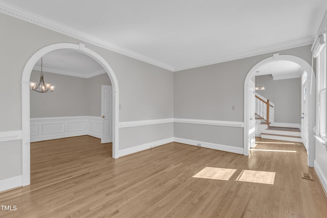 6201 Bayswater Trl, Raleigh, NC 27612 - unfurnished room with a chandelier, light wood-style flooring, stairs, ornamental molding, and arched walkways