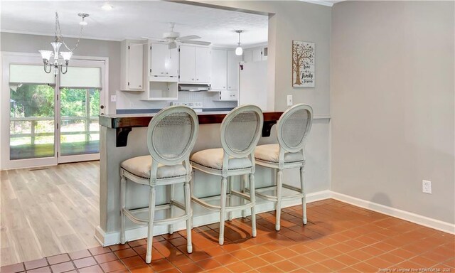1519 Magnolia Dr, Fairmont, NC 28340 - kitchen with white cabinetry, ventilation hood, a ceiling fan, baseboards, and a breakfast bar