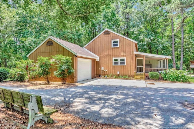 1519 Magnolia Dr, Fairmont, NC 28340 - chalet / cabin featuring a porch, driveway, an outdoor structure, board and batten siding, and a garage