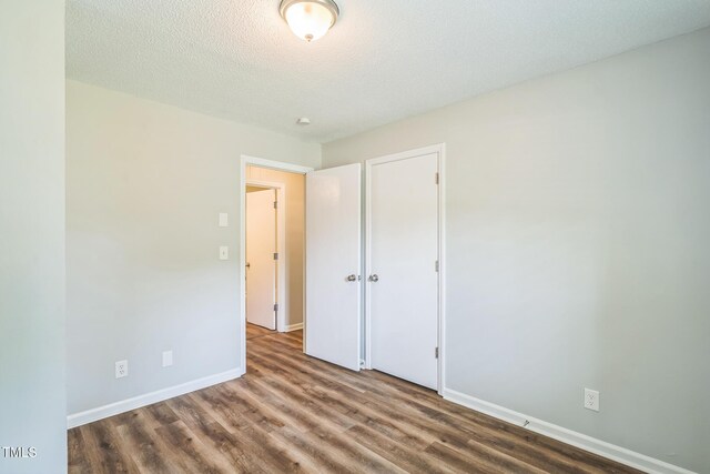 605 Sexton Ave, Zebulon, NC 27597 - unfurnished bedroom with wood finished floors, baseboards, a closet, and a textured ceiling