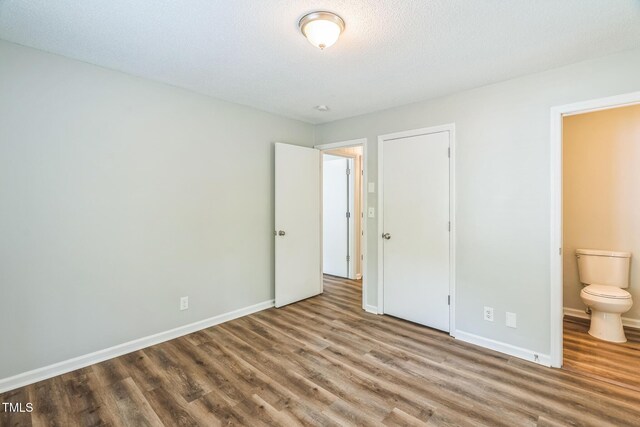 605 Sexton Ave, Zebulon, NC 27597 - unfurnished bedroom featuring wood finished floors, baseboards, and connected bathroom