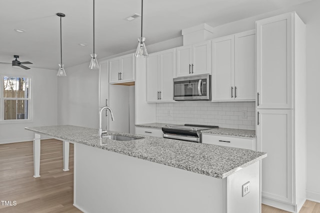 4821 Gossamer Ln Unit 103, Raleigh, NC 27616 - kitchen with stainless steel appliances, a ceiling fan, a sink, light wood-style floors, and a center island with sink