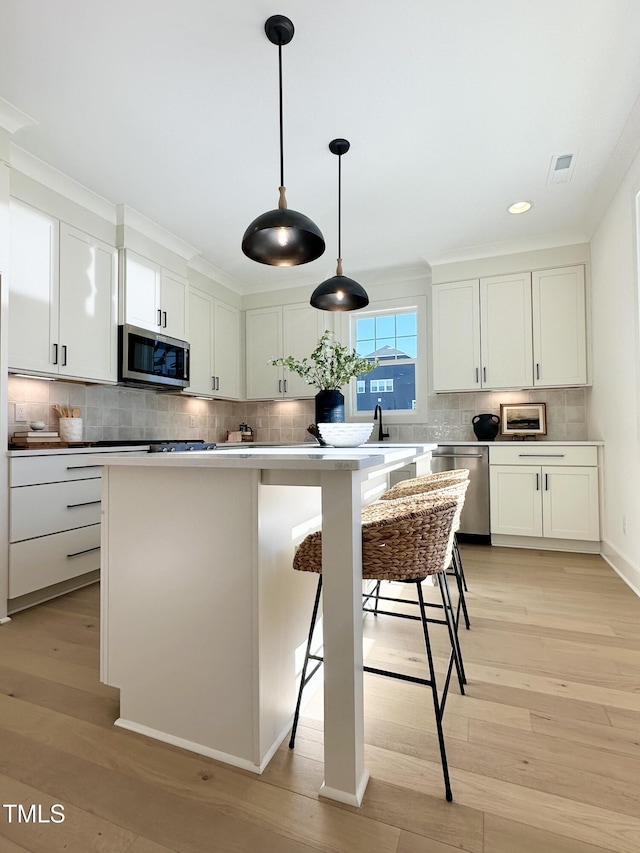 974 Double Helix Rd, Apex, NC 27523 - kitchen with appliances with stainless steel finishes, backsplash, white cabinetry, light wood-style floors, and hanging light fixtures