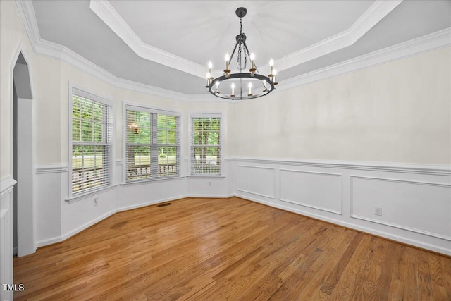 618 Durwood Dr, Raleigh, NC 27603 - unfurnished dining area with a chandelier, light wood-style floors, crown molding, a raised ceiling, and a wainscoted wall