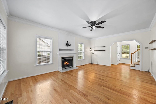 618 Durwood Dr, Raleigh, NC 27603 - unfurnished living room featuring light wood finished floors, ceiling fan, a fireplace with flush hearth, ornamental molding, and stairs