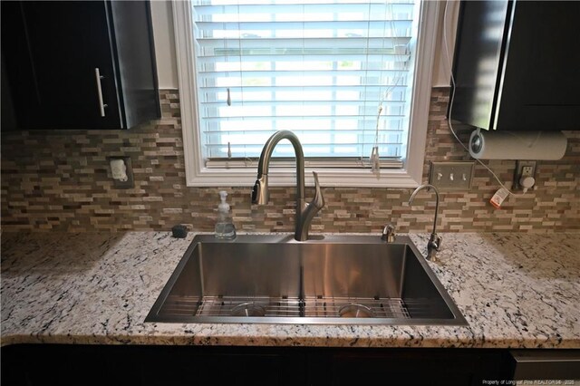 579 Wedgefield Dr, Raeford, NC 28376 - kitchen view of a sink, decorative backsplash, dark cabinetry, and light stone counters