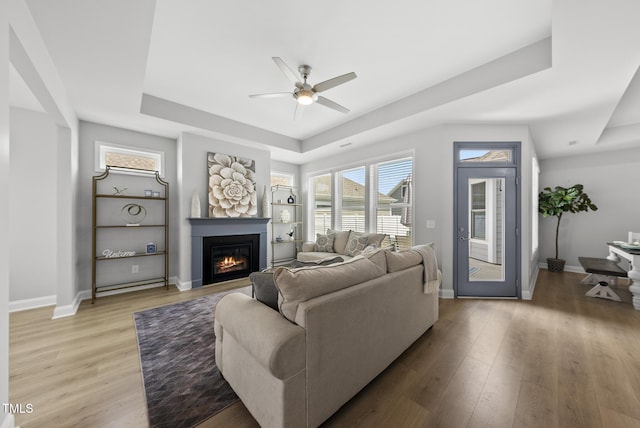 1727 Pinecliff Ct, Fuquay Varina, NC 27526 - living room with a raised ceiling, ceiling fan, light wood-style floors, a glass covered fireplace, and plenty of natural light