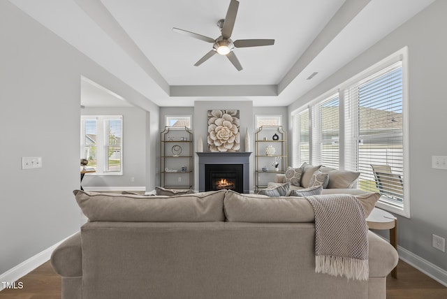 1727 Pinecliff Ct, Fuquay Varina, NC 27526 - living area with a ceiling fan, a lit fireplace, a tray ceiling, and plenty of natural light
