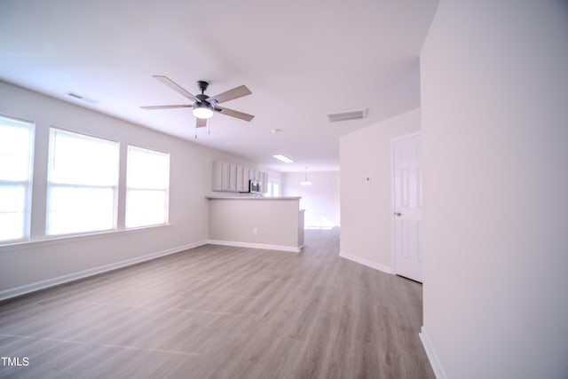 8021 Wesley Farm Dr, Raleigh, NC 27616 - unfurnished living room with ceiling fan, baseboards, and light wood-style flooring