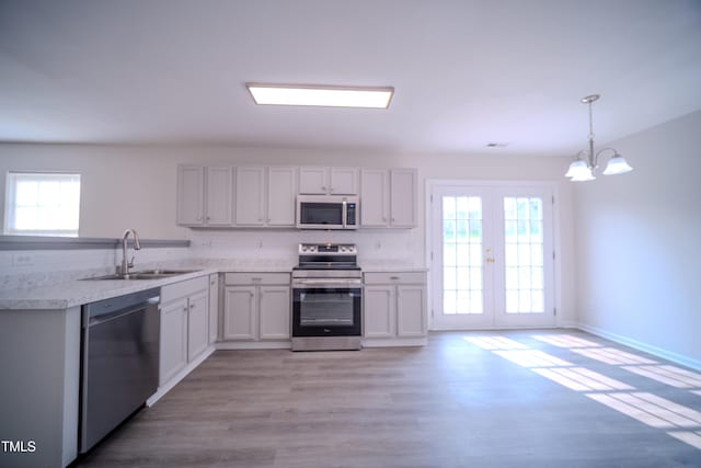 8021 Wesley Farm Dr, Raleigh, NC 27616 - kitchen with stainless steel appliances, a sink, light countertops, a chandelier, and light wood-style flooring