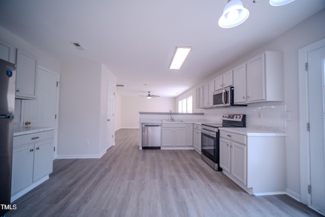 8021 Wesley Farm Dr, Raleigh, NC 27616 - kitchen featuring appliances with stainless steel finishes, a sink, a peninsula, light countertops, and light wood-style flooring