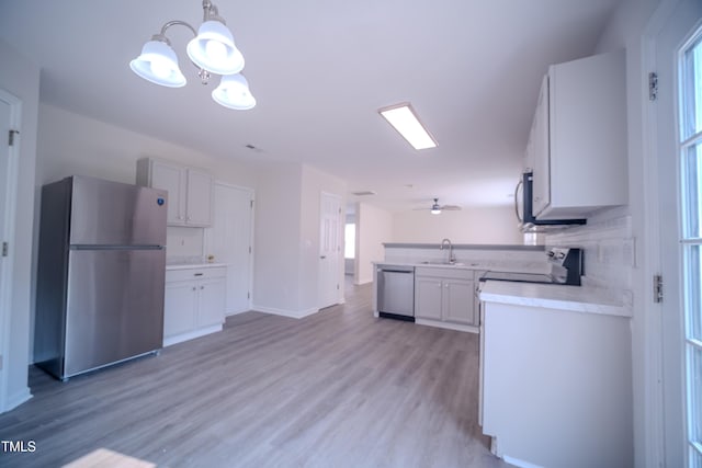 8021 Wesley Farm Dr, Raleigh, NC 27616 - kitchen with appliances with stainless steel finishes, light countertops, a sink, light wood-style floors, and decorative light fixtures