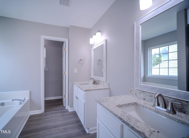 8021 Wesley Farm Dr, Raleigh, NC 27616 - full bath with two vanities, wood finished floors, a garden tub, and baseboards