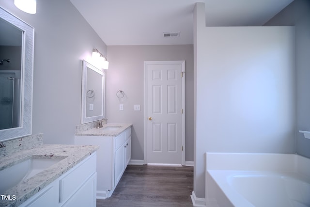 8021 Wesley Farm Dr, Raleigh, NC 27616 - bathroom with two vanities, wood finished floors, a garden tub, and baseboards
