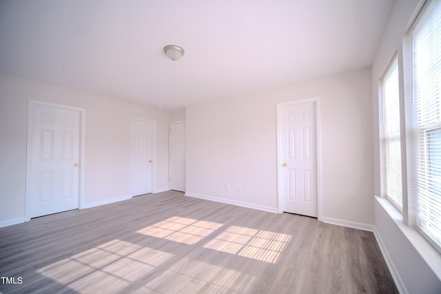 8021 Wesley Farm Dr, Raleigh, NC 27616 - unfurnished bedroom with wood finished floors, multiple windows, and baseboards