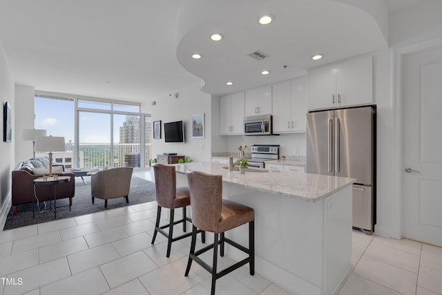 301 Fayetteville St Unit 2611, Raleigh, NC 27601 - kitchen with appliances with stainless steel finishes, open floor plan, a sink, white cabinetry, and a kitchen bar