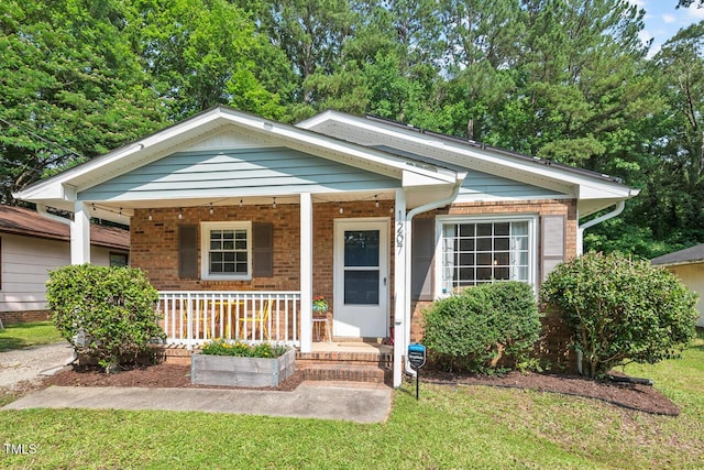 1207 Grant St, Durham, NC 27701 - view of front of house featuring covered porch, a front lawn, and brick siding