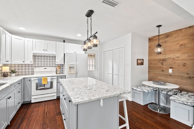 1207 Grant St, Durham, NC 27701 - kitchen featuring white appliances, dark wood-style flooring, recessed lighting, decorative backsplash, and light stone countertops