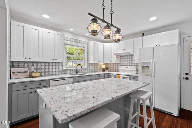 1207 Grant St, Durham, NC 27701 - kitchen featuring white appliances, a sink, under cabinet range hood, gray cabinetry, and a breakfast bar area