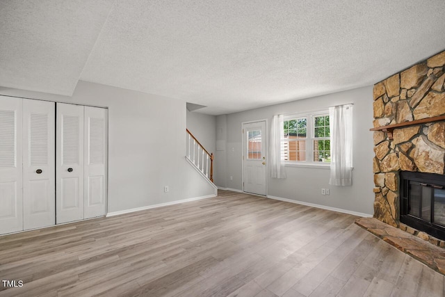7731 Kingsberry Ct, Raleigh, NC 27615 - unfurnished living room featuring a textured ceiling, stairway, light wood-style floors, and a fireplace