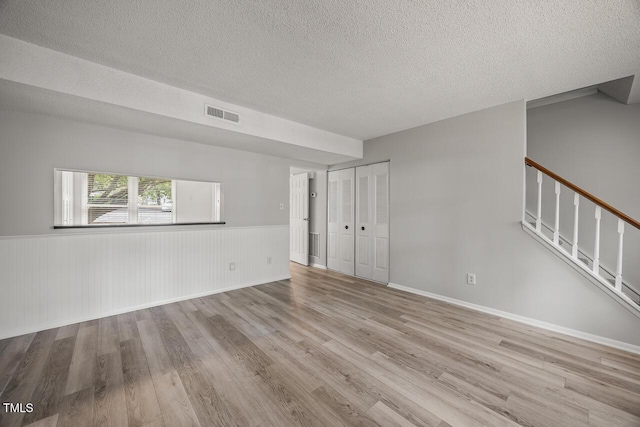 7731 Kingsberry Ct, Raleigh, NC 27615 - spare room with wood finished floors, a textured ceiling, a wainscoted wall, and stairway