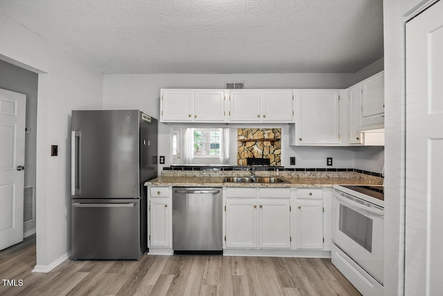 7731 Kingsberry Ct, Raleigh, NC 27615 - kitchen featuring stainless steel appliances, light wood-style flooring, exhaust hood, white cabinetry, and a textured ceiling