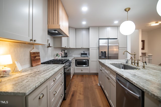 5012 Skidmore St, Raleigh, NC 27609 - kitchen featuring appliances with stainless steel finishes, dark wood-style flooring, light stone counters, pendant lighting, and tasteful backsplash