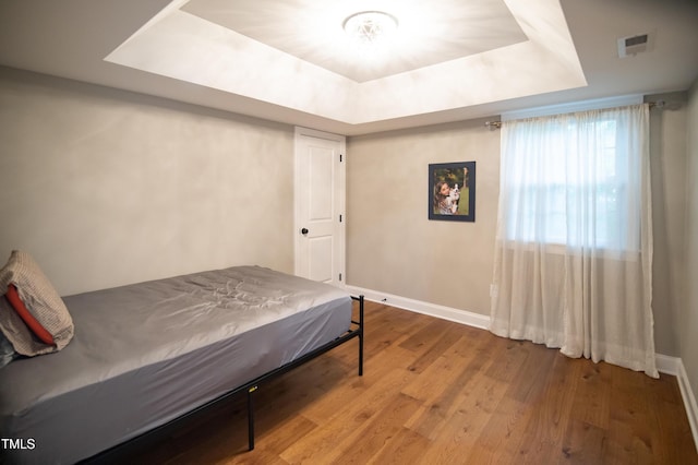 5012 Skidmore St, Raleigh, NC 27609 - bedroom featuring a tray ceiling and wood finished floors