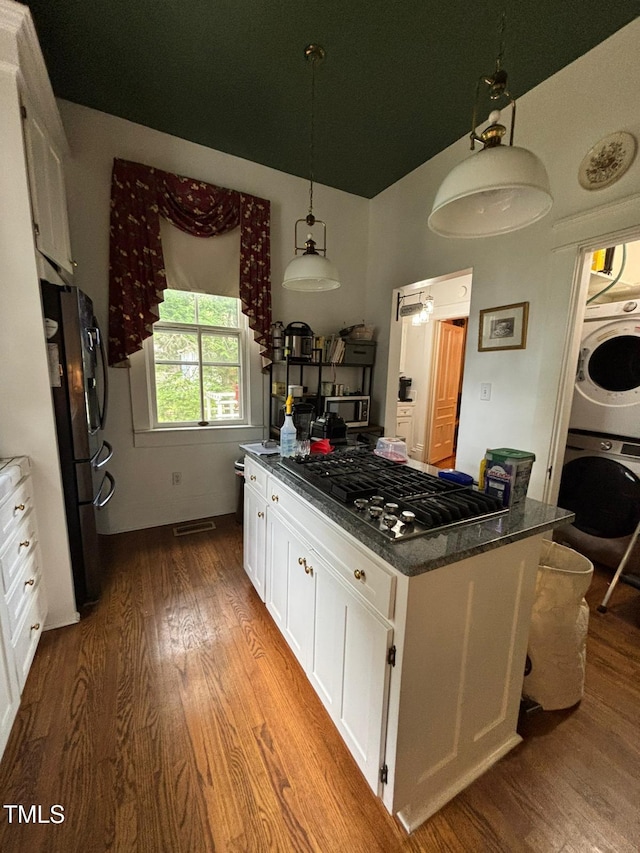 331 N Main St, Warrenton, NC 27589 - kitchen featuring estacked washer and dryer, freestanding refrigerator, dark wood-type flooring, white cabinetry, and gas cooktop