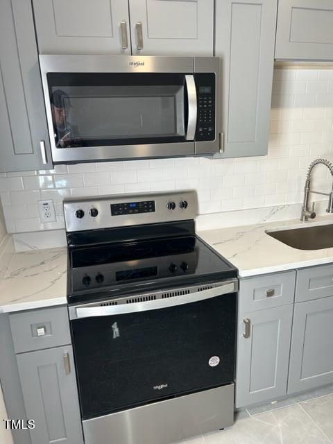 407 Bledsoe Ave, Raleigh, NC 27601 - kitchen featuring stainless steel appliances, gray cabinetry, backsplash, and light stone counters