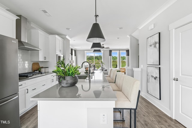 659 Bandon Aly, Cary, NC 27513 - kitchen featuring wall chimney range hood, stainless steel appliances, a sink, open floor plan, and wood finished floors