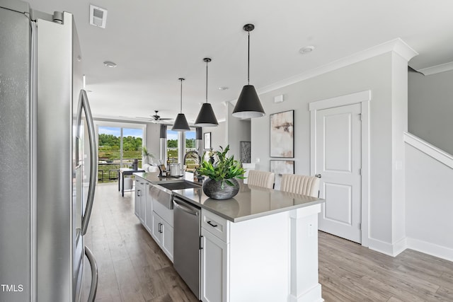 659 Bandon Aly, Cary, NC 27513 - kitchen featuring appliances with stainless steel finishes, a sink, light wood-type flooring, open floor plan, and ornamental molding