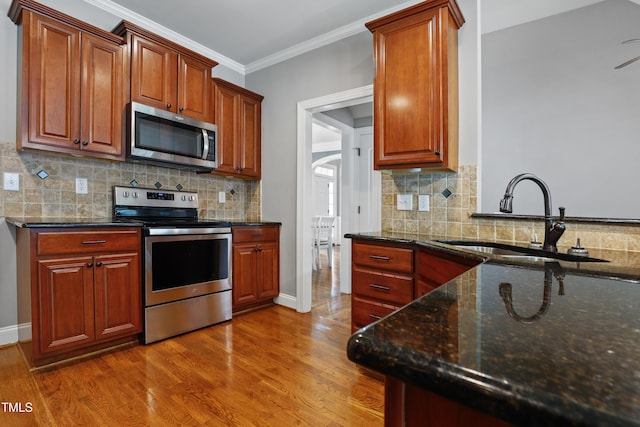 37 Meadow Oaks Cir, Smithfield, NC 27577 - kitchen featuring stainless steel appliances, a sink, ornamental molding, wood finished floors, and dark stone counters