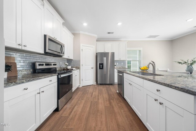 304 Azalea Gaze Dr, Youngsville, NC 27596 - kitchen featuring stainless steel appliances, a sink, crown molding, white cabinets, and dark stone counters