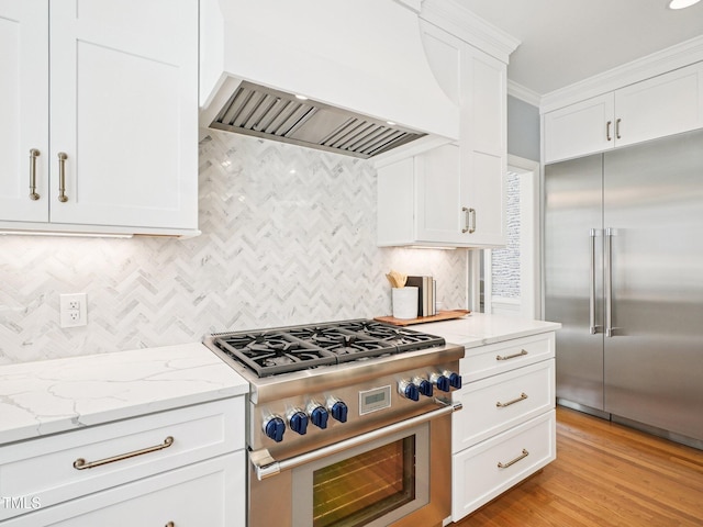 305 Promontory Point Dr, Cary, NC 27513 - kitchen featuring high quality appliances, premium range hood, white cabinetry, backsplash, and light stone countertops