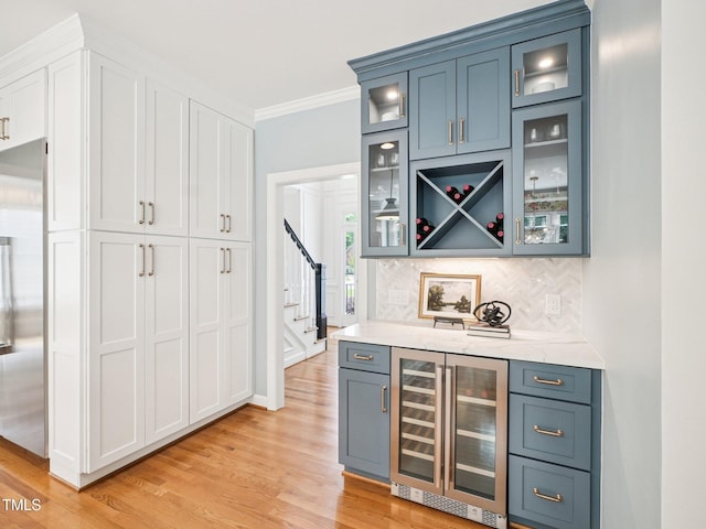 305 Promontory Point Dr, Cary, NC 27513 - indoor dry bar featuring beverage cooler, light wood-style flooring, ornamental molding, stairs, and tasteful backsplash