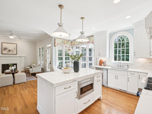 305 Promontory Point Dr, Cary, NC 27513 - kitchen featuring stainless steel appliances, a sink, light wood-style flooring, crown molding, and decorative backsplash