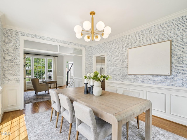305 Promontory Point Dr, Cary, NC 27513 - dining area with stairs, ornamental molding, a chandelier, wood finished floors, and a wainscoted wall