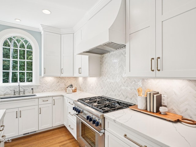 305 Promontory Point Dr, Cary, NC 27513 - kitchen with custom range hood, stainless steel range, a sink, white cabinets, and light stone counters