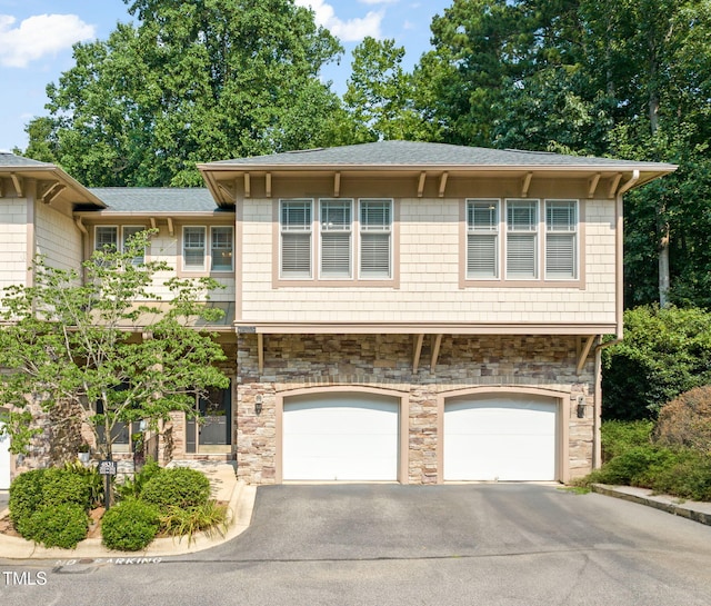 4831 Crestmore Rd Unit 202, Raleigh, NC 27612 - view of front facade featuring stone siding, a garage, driveway, and roof with shingles