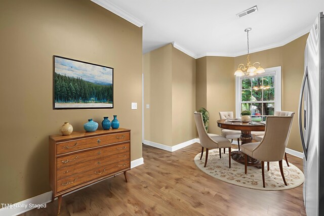 2623 Broad Oaks Pl, Raleigh, NC 27603 - dining room with crown molding, light wood-style floors, a chandelier, and baseboards