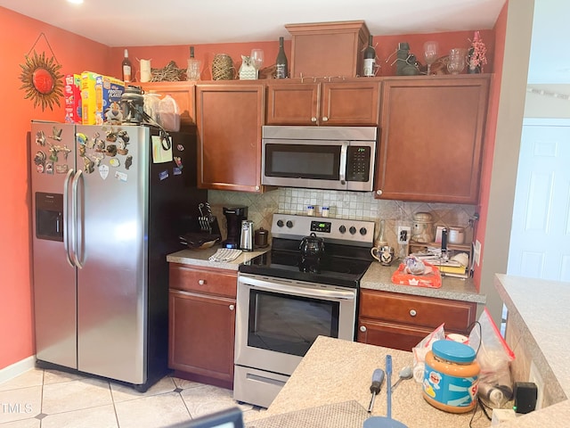 101 Langston Ridge Dr, Angier, NC 27501 - kitchen featuring appliances with stainless steel finishes, light countertops, backsplash, light tile patterned floors, and brown cabinetry