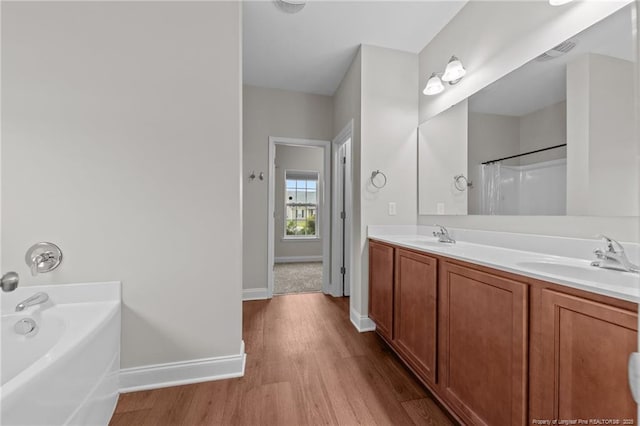 267 Driftwood Ln, Raeford, NC 28376 - bathroom featuring wood finished floors, baseboards, a garden tub, and double vanity