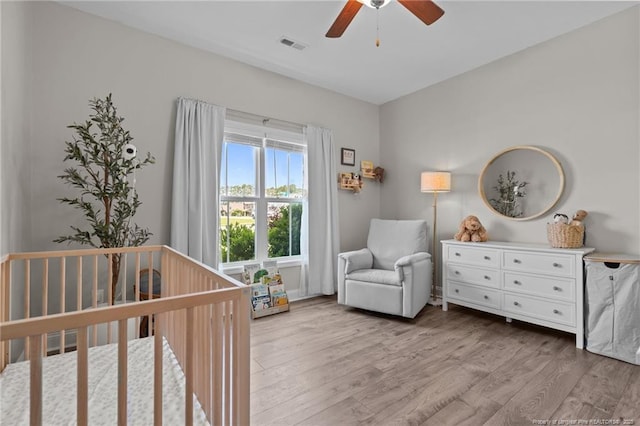 117 Titleist Ct, Raeford, NC 28376 - bedroom with light wood-style floors, a crib, and a ceiling fan