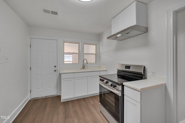 414 Craven St, Durham, NC 27704 - kitchen featuring stainless steel electric range, wall chimney exhaust hood, a sink, light wood finished floors, and white cabinetry