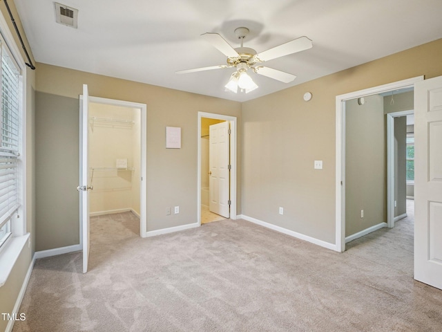 2845 Bennington Dr, Clayton, NC 27520 - unfurnished bedroom featuring light carpet, a walk in closet, multiple windows, and baseboards