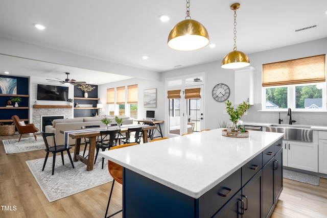 226 Castle Pond Way, Fuquay Varina, NC 27526 - kitchen with ceiling fan, light countertops, a fireplace, white cabinets, and pendant lighting