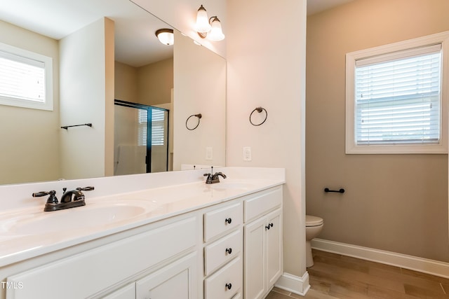 67 Bornean Dr, Garner, NC 27529 - bathroom featuring a stall shower, double vanity, toilet, wood finished floors, and baseboards
