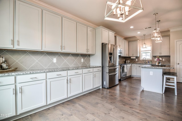 77 Redpine Ct, Clayton, NC 27520 - kitchen with appliances with stainless steel finishes, a chandelier, decorative backsplash, a breakfast bar area, and ornamental molding