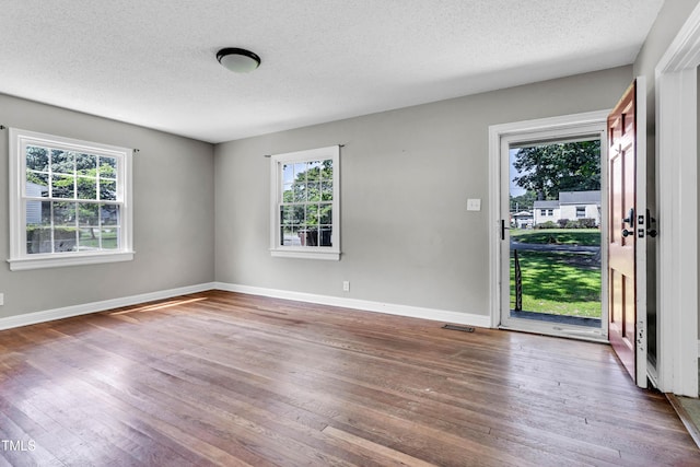 2719 Stratford Dr, Greensboro, NC 27408 - spare room featuring plenty of natural light, hardwood / wood-style flooring, a textured ceiling, and baseboards